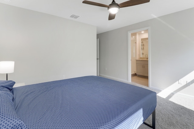 carpeted bedroom featuring ensuite bath, ceiling fan, and sink