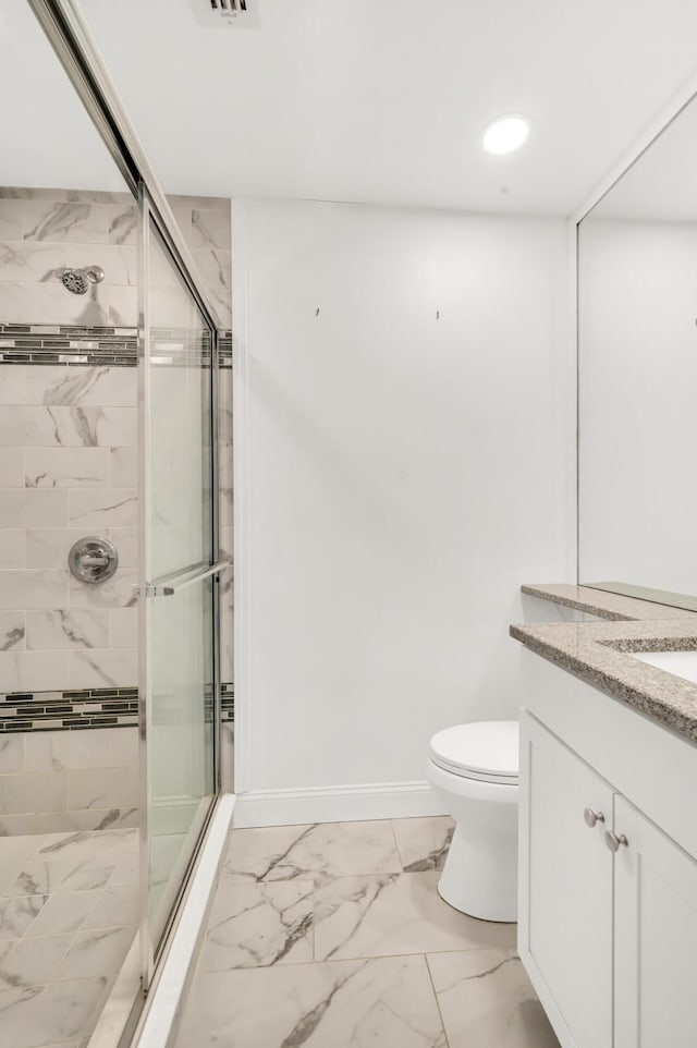 bathroom featuring vanity, toilet, and a shower with door