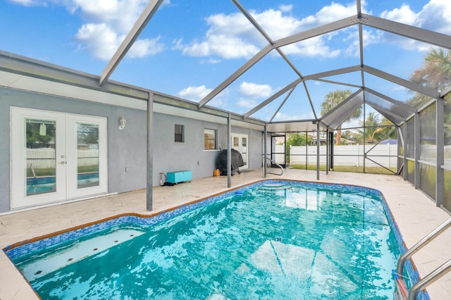 view of pool with french doors, glass enclosure, and a patio area