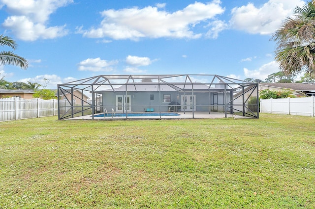 back of house with a lanai, a yard, and a fenced in pool