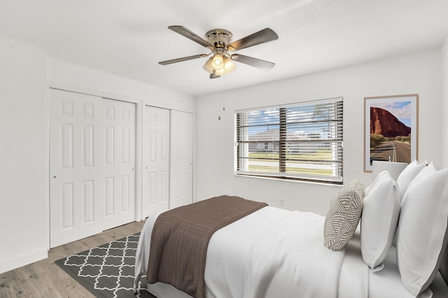 bedroom featuring two closets, light hardwood / wood-style flooring, and ceiling fan