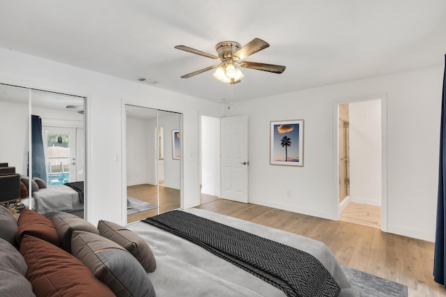 bedroom with ceiling fan, light hardwood / wood-style floors, and multiple closets