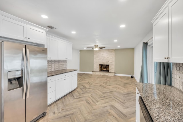 kitchen featuring ceiling fan, stainless steel appliances, tasteful backsplash, dark stone countertops, and white cabinets