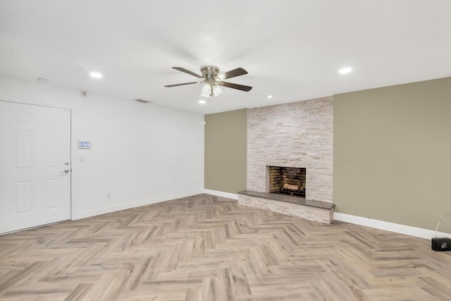 unfurnished living room featuring light parquet flooring, a stone fireplace, and ceiling fan