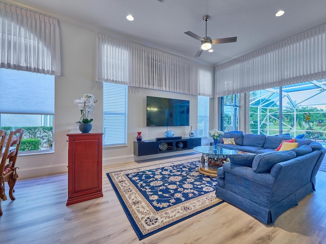 living room with light wood-type flooring, ceiling fan, and ornamental molding