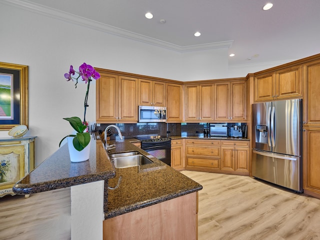 kitchen featuring sink, kitchen peninsula, dark stone counters, appliances with stainless steel finishes, and ornamental molding