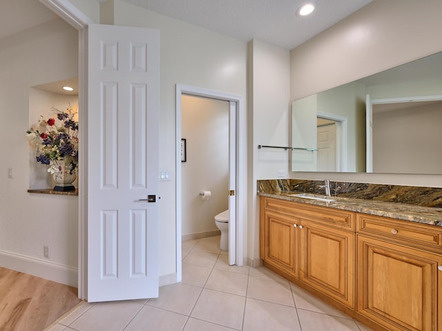 bathroom with toilet, vanity, and tile patterned floors