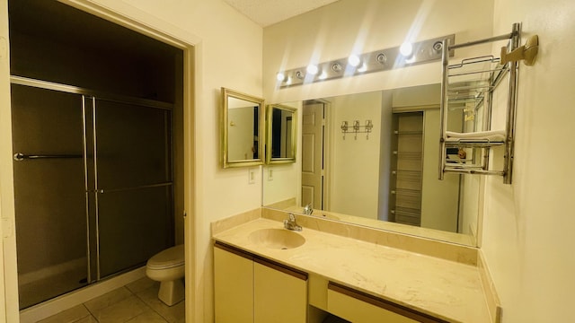 bathroom with tile patterned flooring, vanity, toilet, and a shower with shower door