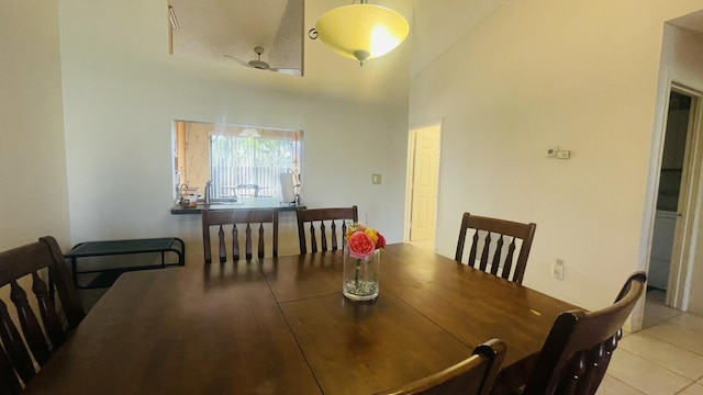 tiled dining room with ceiling fan and a high ceiling