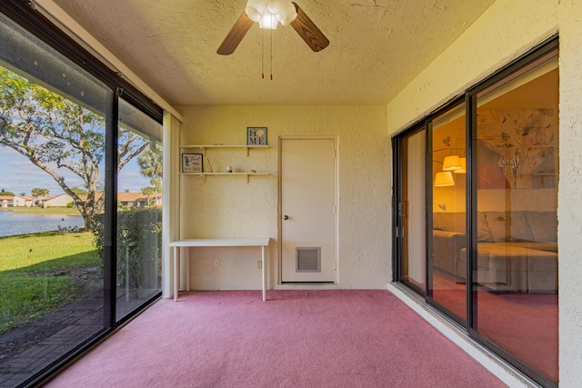 unfurnished sunroom featuring a water view and ceiling fan