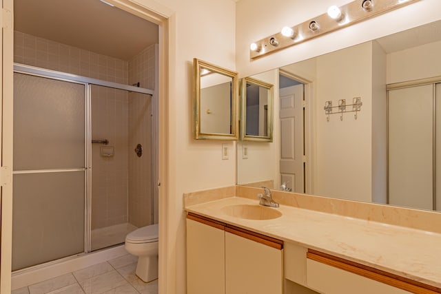 bathroom featuring tile patterned flooring, vanity, toilet, and a shower with door