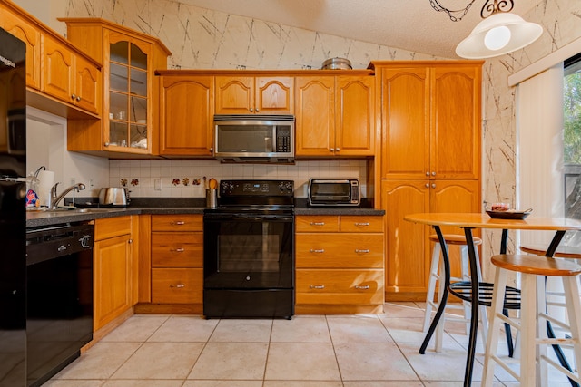 kitchen with sink, a textured ceiling, vaulted ceiling, light tile patterned floors, and black appliances