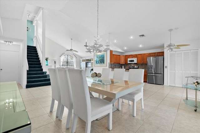 dining space featuring ceiling fan with notable chandelier, vaulted ceiling, and light tile patterned flooring