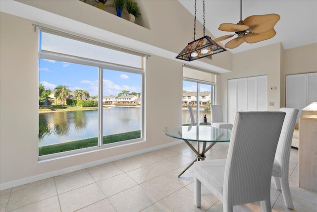 tiled dining room featuring ceiling fan and a water view