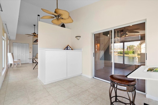 interior space with light tile patterned floors, a towering ceiling, and ceiling fan