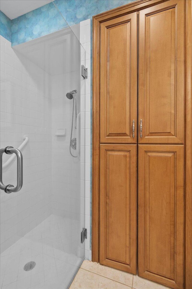 bathroom with a shower with door and tile patterned flooring