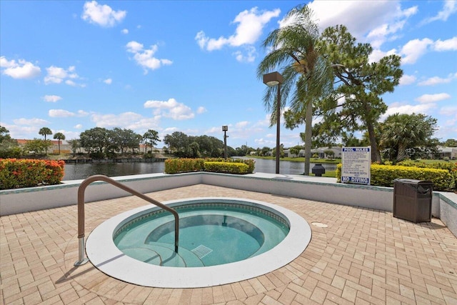 view of pool with a water view and a hot tub