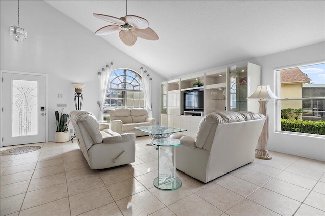 tiled living room with high vaulted ceiling and ceiling fan with notable chandelier