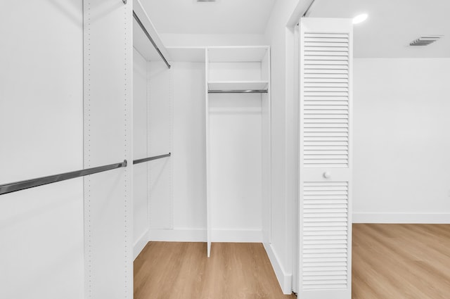 walk in closet with light hardwood / wood-style floors