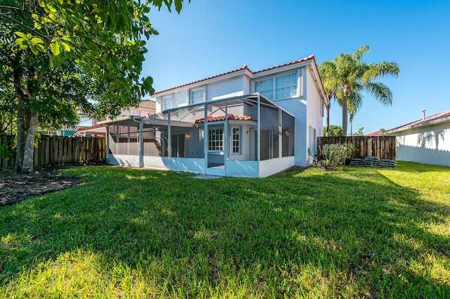 rear view of property with a lanai and a lawn