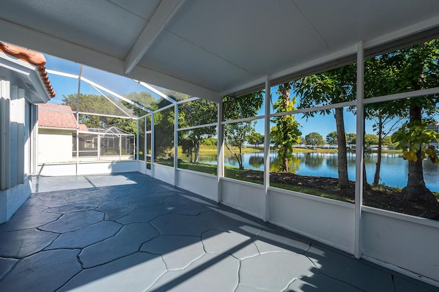 unfurnished sunroom featuring beam ceiling and a water view