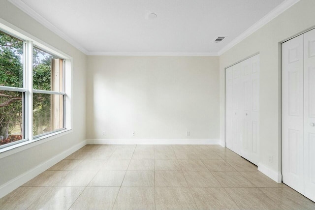 unfurnished bedroom with multiple closets, crown molding, and light tile patterned flooring