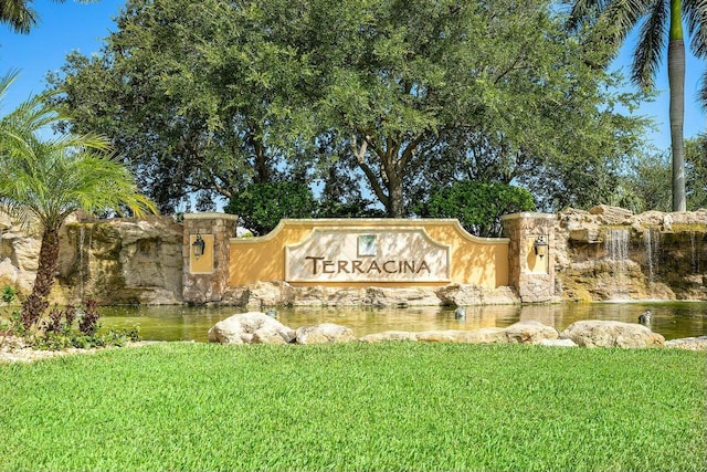 community / neighborhood sign with a water view and a yard