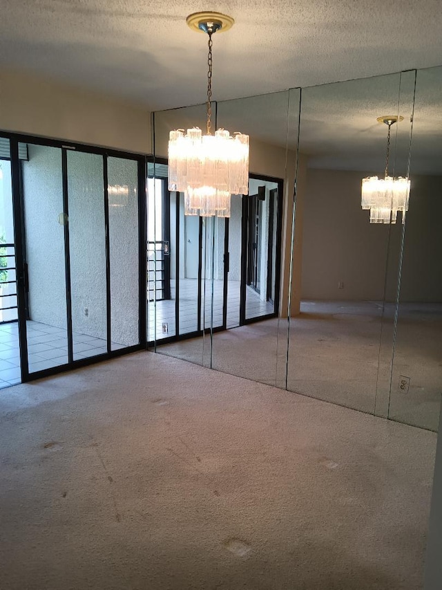 interior space featuring a textured ceiling, carpet flooring, and a chandelier