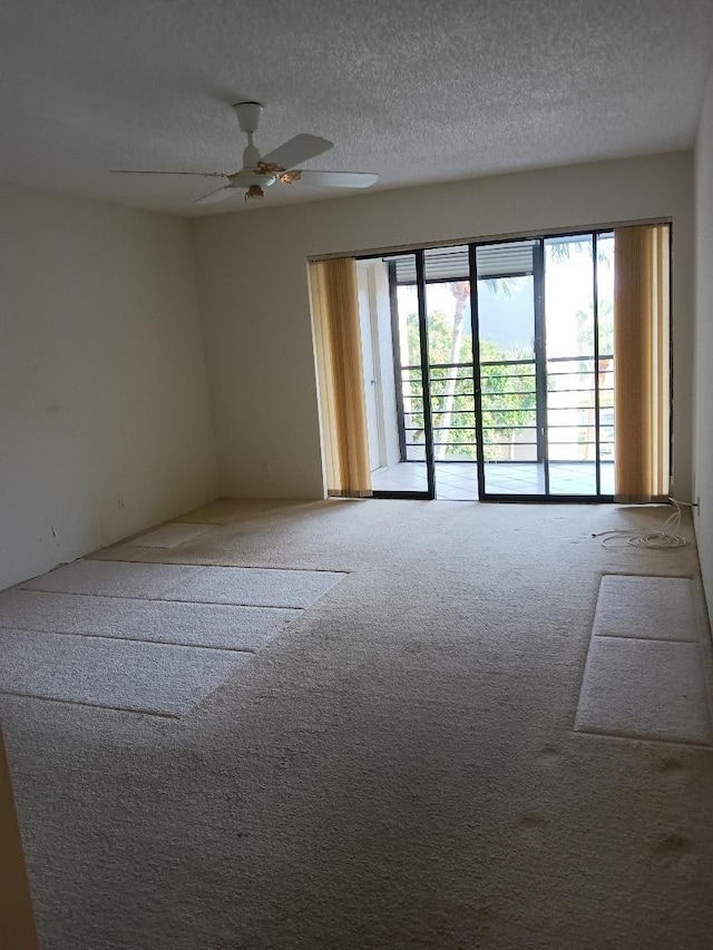 carpeted spare room featuring a textured ceiling and ceiling fan