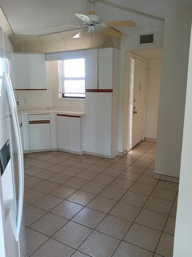 interior space with light countertops, visible vents, a ceiling fan, white cabinets, and white fridge with ice dispenser