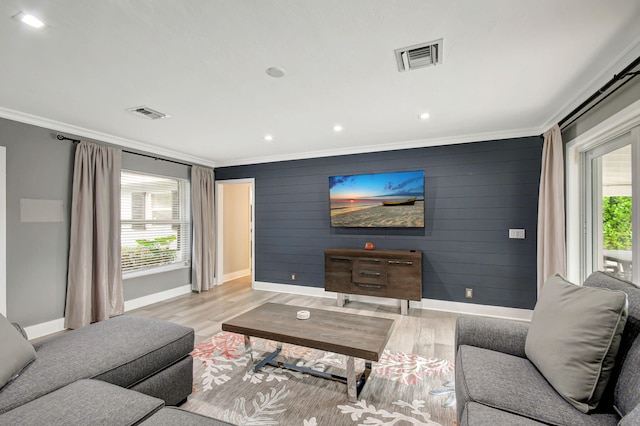 living room with a healthy amount of sunlight, light wood-type flooring, and crown molding