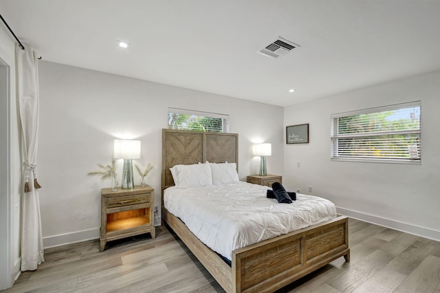 bedroom with light hardwood / wood-style floors and multiple windows