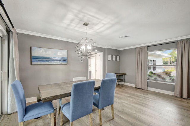 dining space featuring crown molding, a notable chandelier, and light wood-type flooring