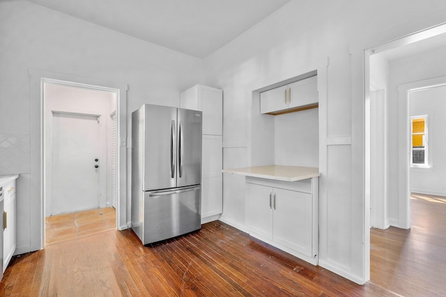 kitchen featuring stainless steel fridge, dark hardwood / wood-style flooring, and white cabinetry