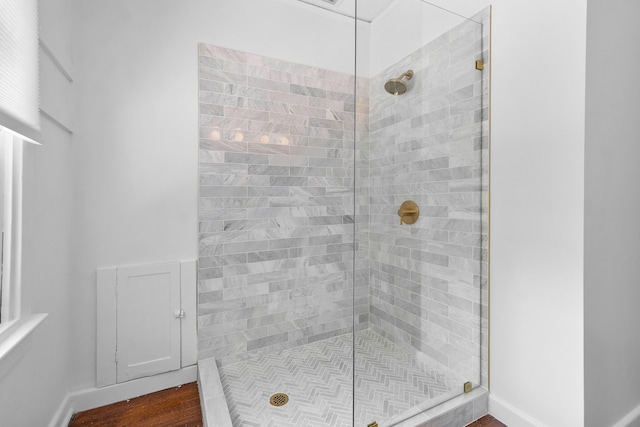 bathroom with tiled shower and hardwood / wood-style floors