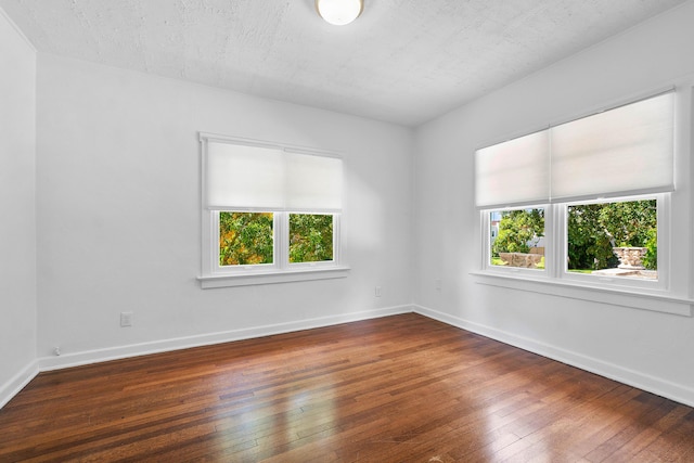 empty room featuring a textured ceiling and dark hardwood / wood-style floors