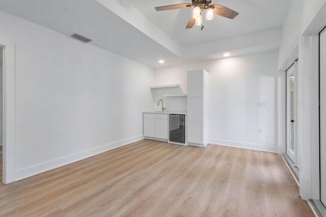 unfurnished living room featuring ceiling fan, light hardwood / wood-style flooring, beverage cooler, and sink