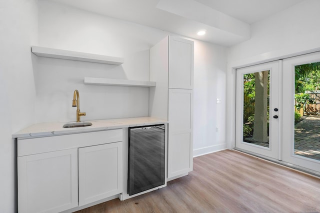 kitchen with light hardwood / wood-style flooring, white cabinets, beverage cooler, and french doors