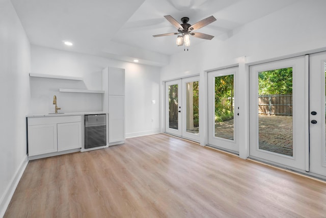 unfurnished living room with french doors, light hardwood / wood-style floors, wine cooler, and sink