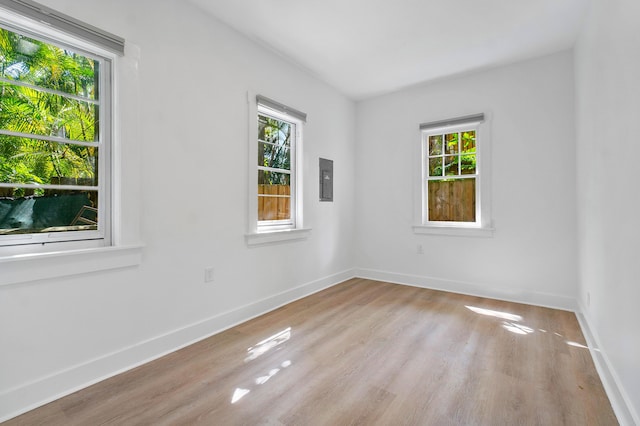 unfurnished room with electric panel and light hardwood / wood-style flooring