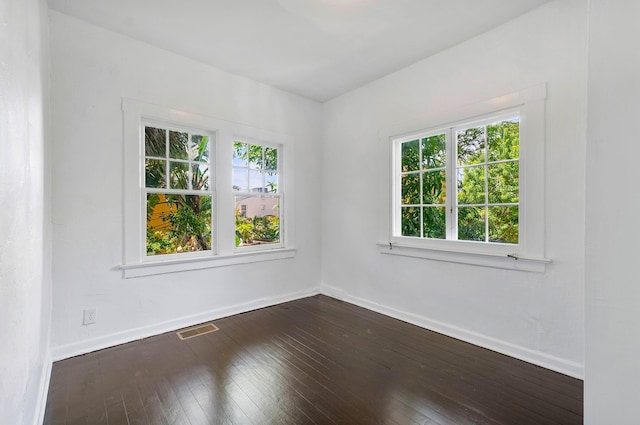 unfurnished room featuring plenty of natural light and dark hardwood / wood-style floors