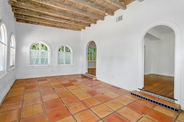 tiled empty room featuring beamed ceiling, high vaulted ceiling, and wooden ceiling