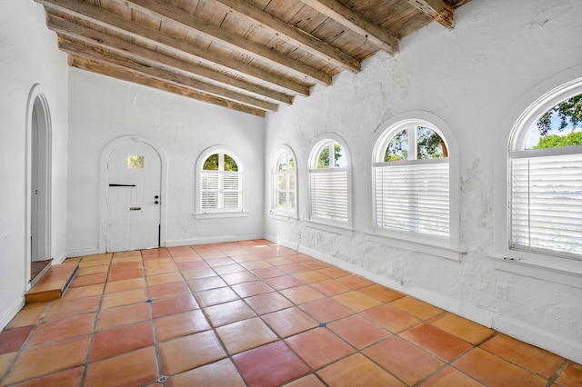 unfurnished sunroom featuring vaulted ceiling with beams, plenty of natural light, and wood ceiling