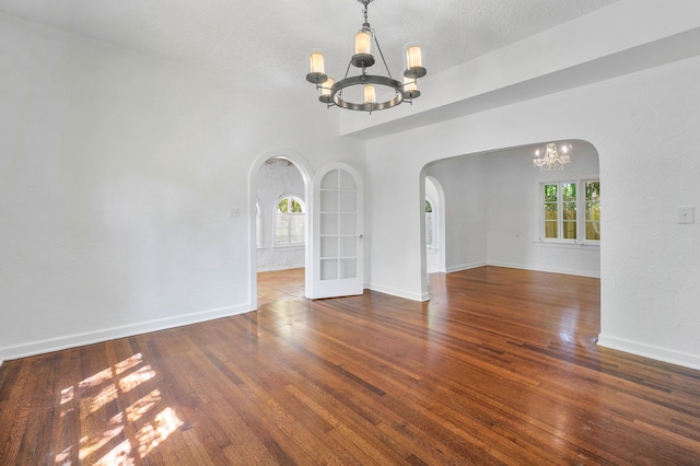 empty room with dark hardwood / wood-style floors, a textured ceiling, and a chandelier