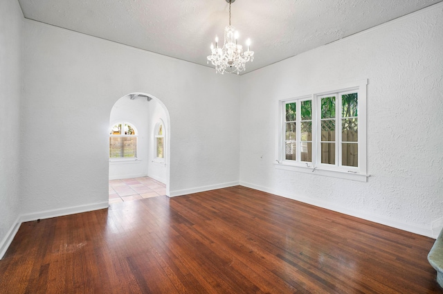 unfurnished room featuring wood-type flooring, a textured ceiling, and an inviting chandelier