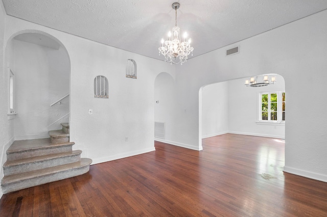 unfurnished room with dark hardwood / wood-style floors, a textured ceiling, and a chandelier