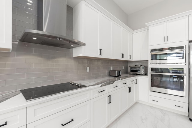 kitchen with black electric stovetop, wall chimney exhaust hood, light stone countertops, double oven, and white cabinetry