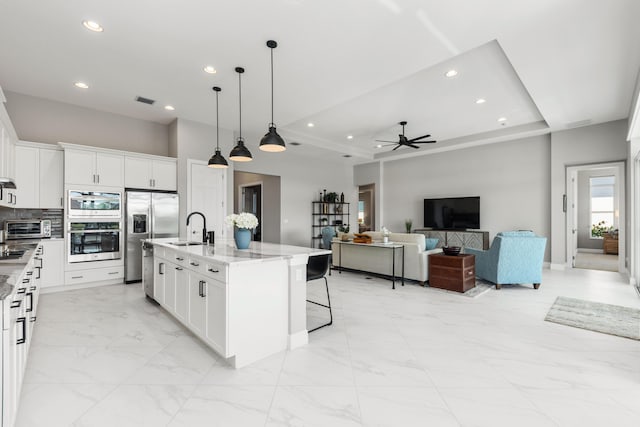 kitchen featuring sink, light stone counters, stainless steel refrigerator with ice dispenser, a kitchen island with sink, and white cabinets