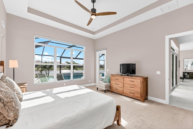 bedroom with light carpet, a tray ceiling, and ceiling fan