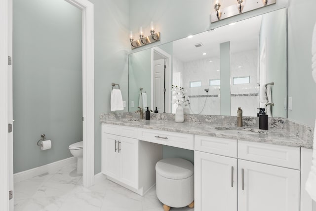 bathroom with tiled shower, vanity, and toilet